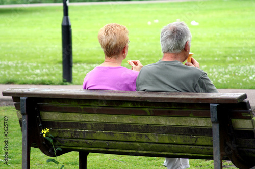 Retired couple eating ice-cream in the park