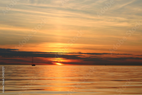 Sunset with a sailing yacht and water reflection