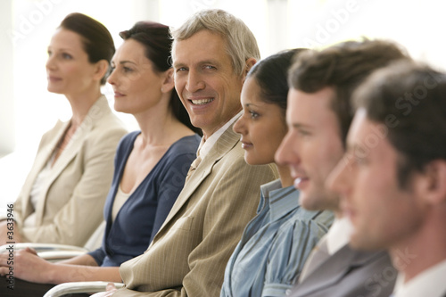 Mature businessman in seated line with colleagues