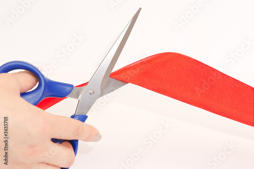 Scissors cutting a red tape