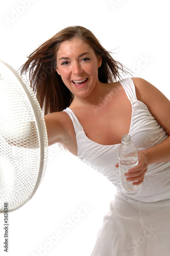 A woman in white leaning against a fan to cool off