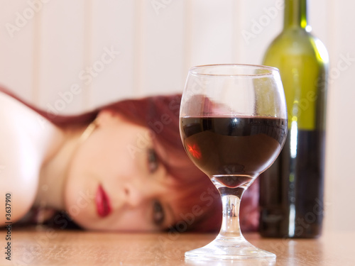 The girl laying on a table and a glass with wine