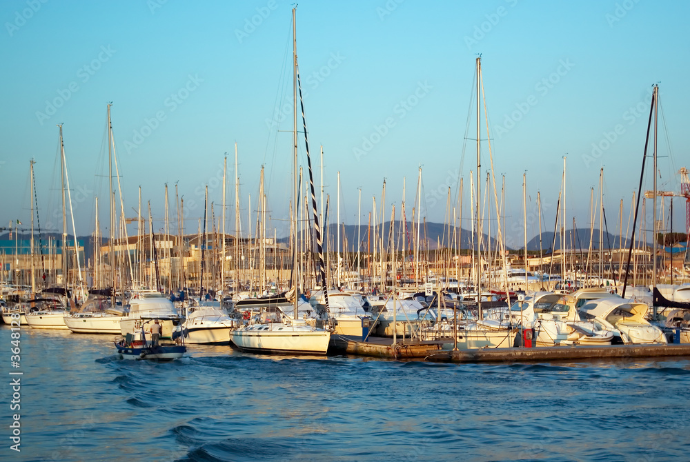 Yachts and sailboats in a port at sunset.