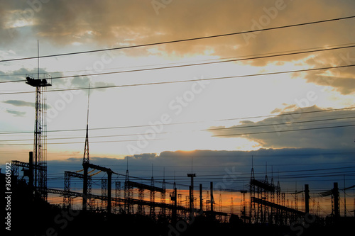 electric wires of power station at sunset beams