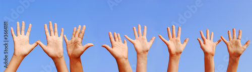 Row of hands with open palms on blue sky background #3664181