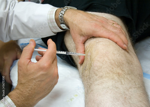 Doctor Giving Injection in the Knee of a Patient