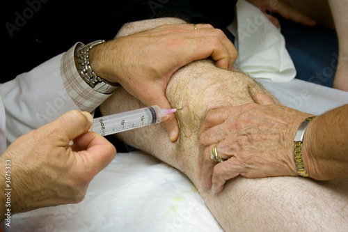 Doctor Giving Injection in the Knee of a Patient