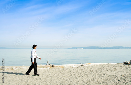 A businessman walking along the beach alone