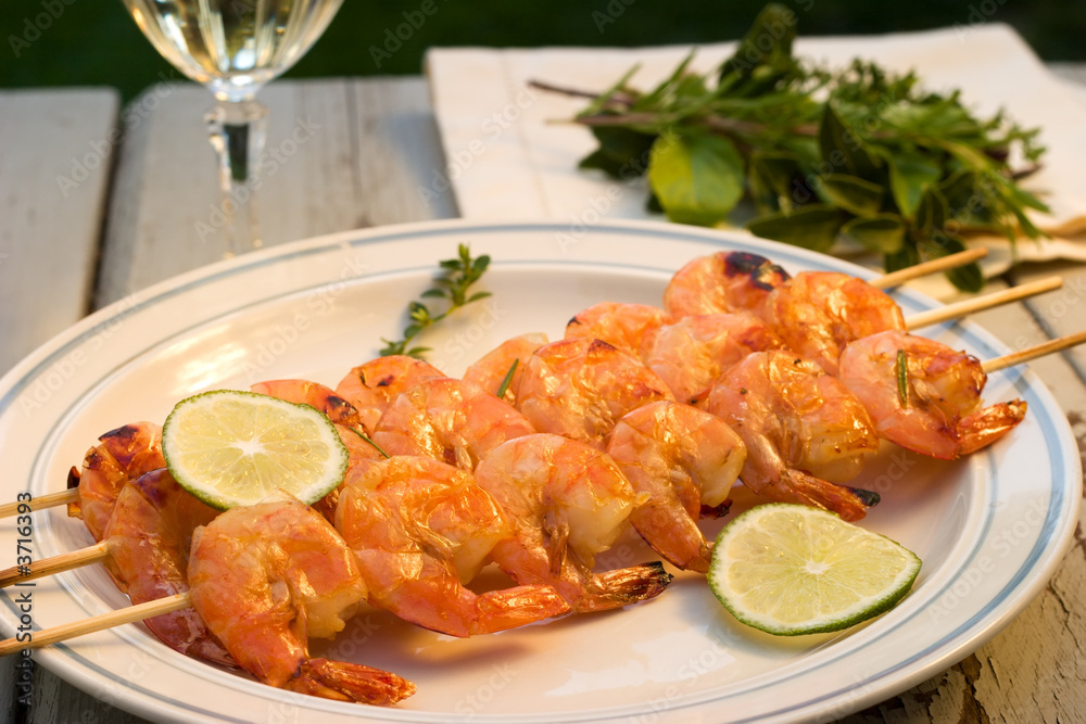 Grilled shrimps on bamboo sticks with glass of white wine