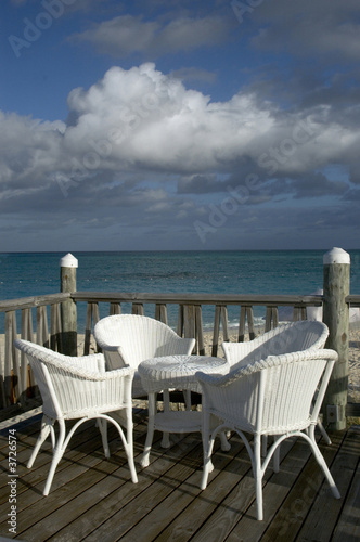 deck by the sea with wicker chairs table blue sky beach