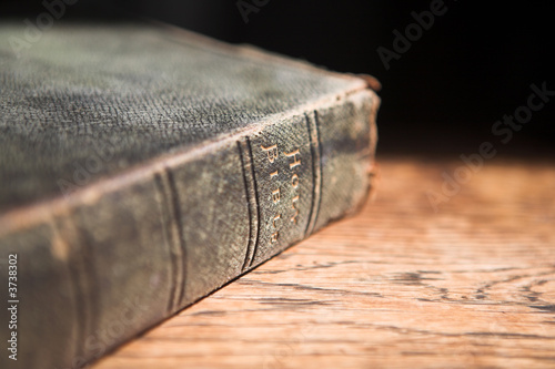Leather covered old bible lying on a wooden table 