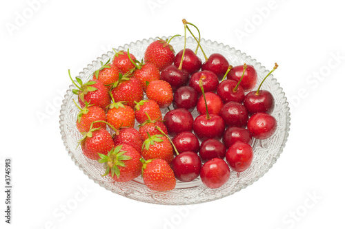 Strawberries and cherries on a glass dish, isolated on white