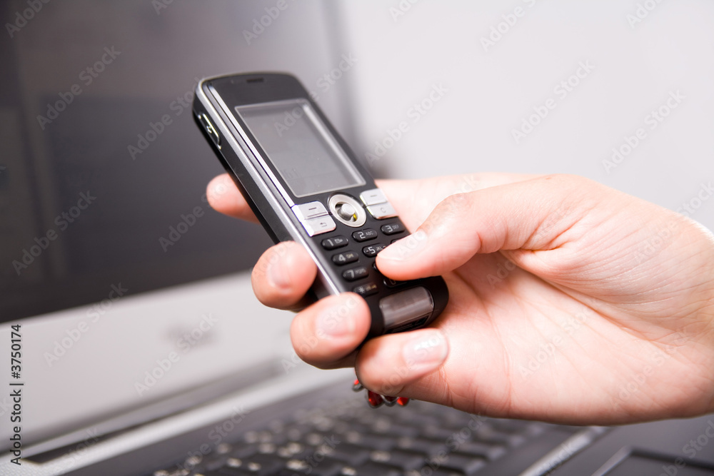 woman holding cell phone over the notebook's keyboard woman holding cell phone over the notebook's keyboard