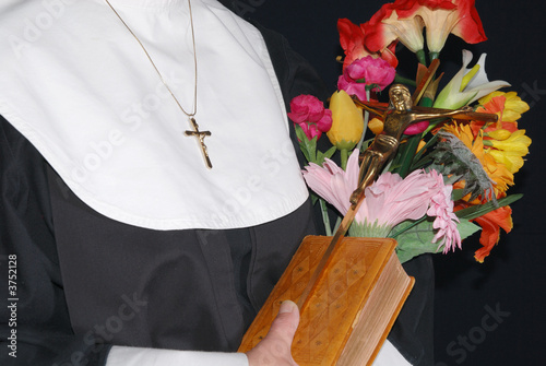 Middle aged devout nun  holding on to bible, cross  photo