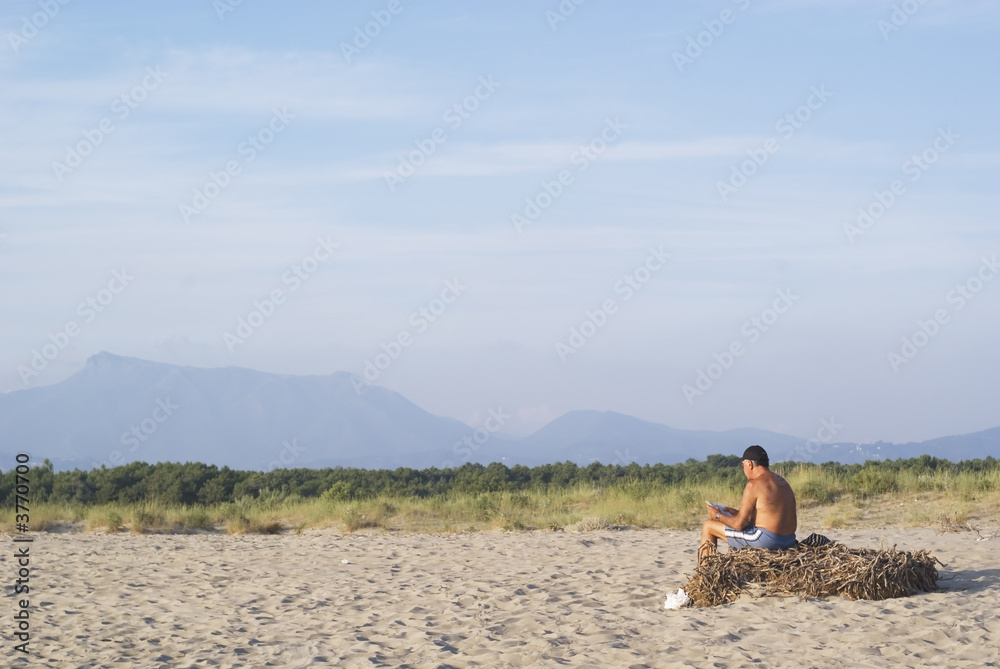Senior man relaxes in a wild beach at sunset