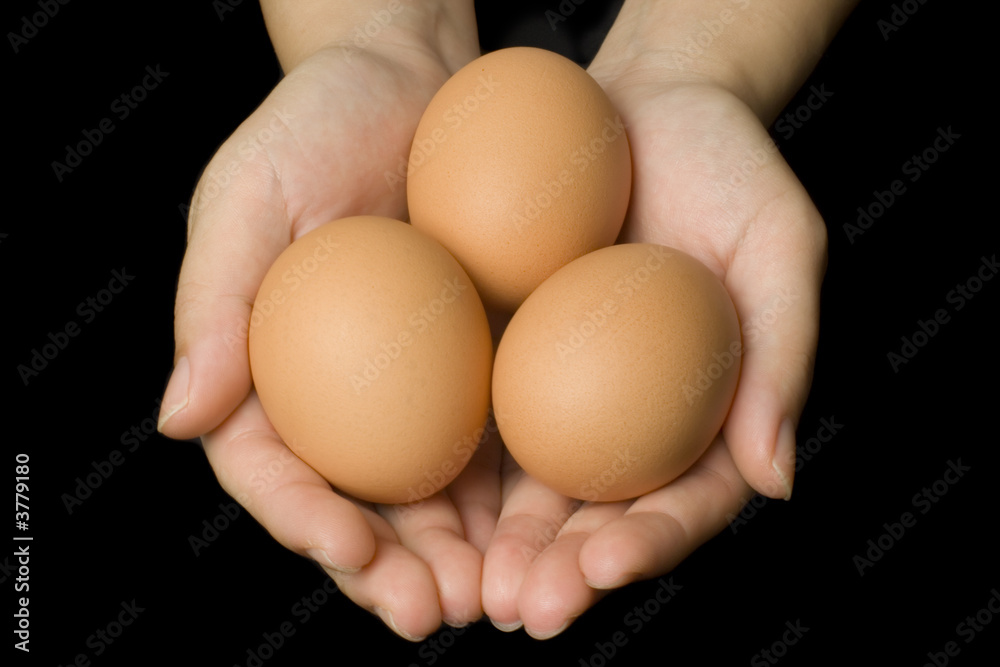 Hands holding three eggs isolated on black background.. Hands holding three eggs isolated on black background..