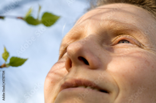 Obraz na plátně Woman and branch of birch tree with leaves is expanding