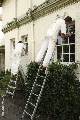 Two painters decorating the exterior of a house
