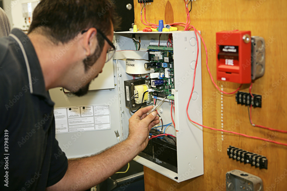 electrician wiring a fire alarm system  - obrazy, fototapety, plakaty 