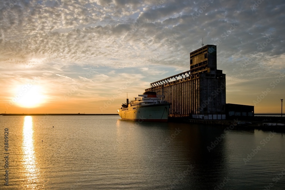 Old ship and grain elevator at sunset