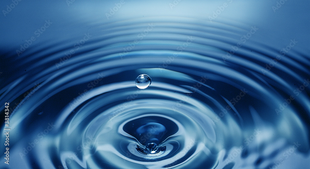 single water drop about to splash onto water's blue surface below single water drop about to splash onto water's blue surface below