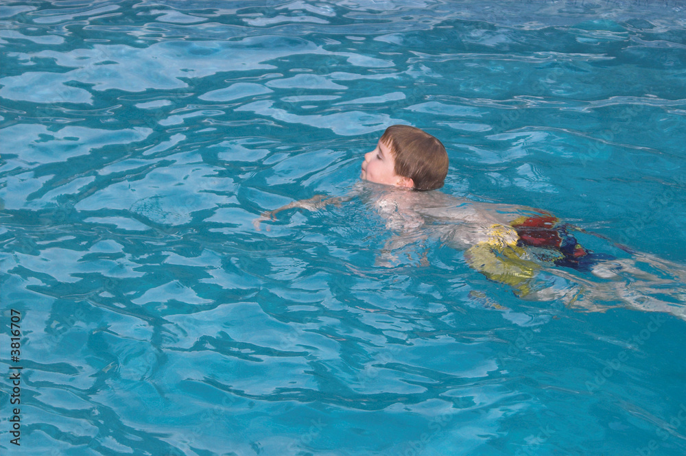 A little boy swimming in a pool.