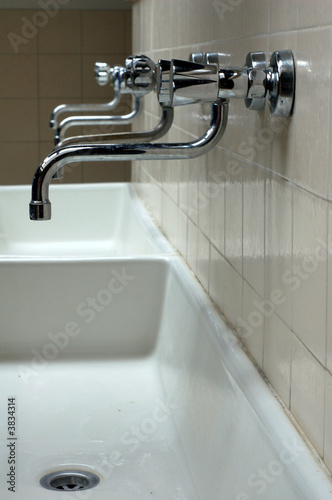 A row of faucets in a community laundry room.
