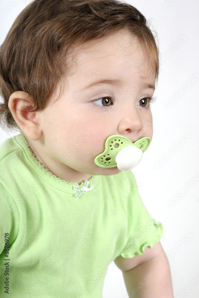 Baby with a green pacifier in its mouth Baby with a green pacifier in its mouth