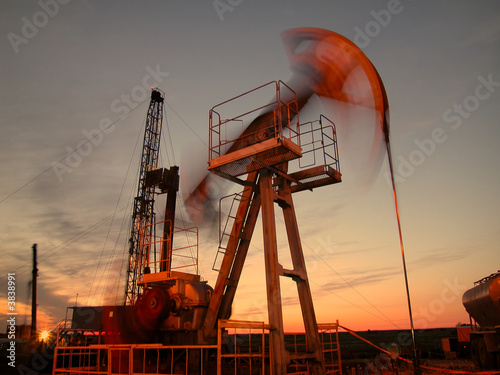 Silhouette of swinging oil pump in evening sky