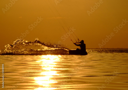 Silhouette of a kitesurf on a gulf on a sunset