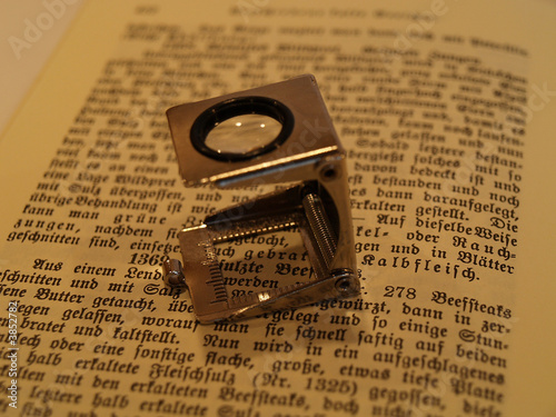 Fadenzähler, Lupe auf einem aufgeschlagenem Buch 