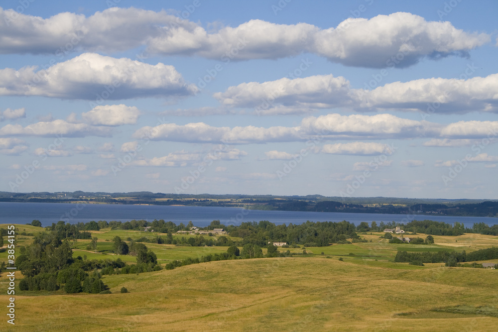 Fototapeta premium Landscape of fields and lake with clouds, captured in Latvia