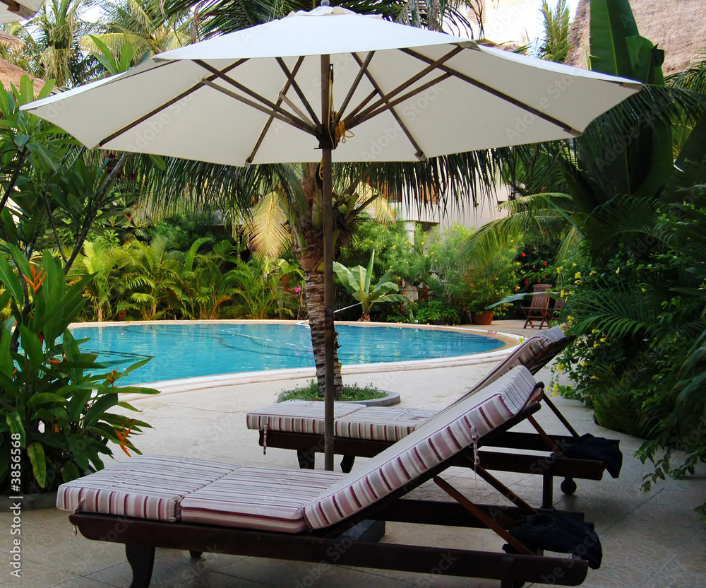 chairs under umbrella at the poolside