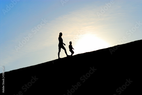 Silhouette of two girls walking up the hill