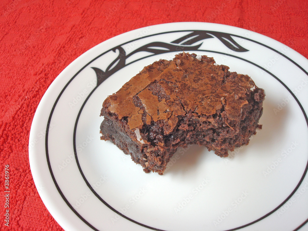Brownie on a white plate set on a red placemat Brownie on a white plate set on a red placemat
