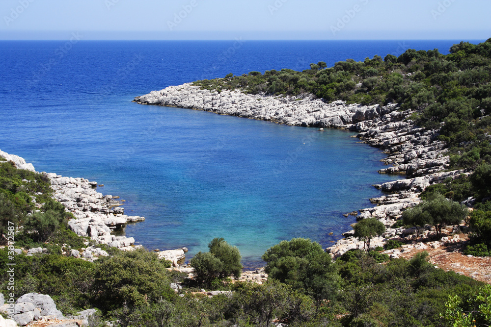 sunny day on a rocky coastline with azure sea water .