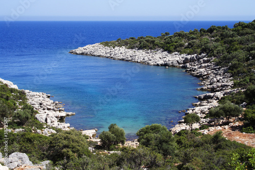 sunny day on a rocky coastline with azure sea water .