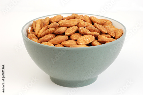 A bowl of shelled almond nuts on a white background.