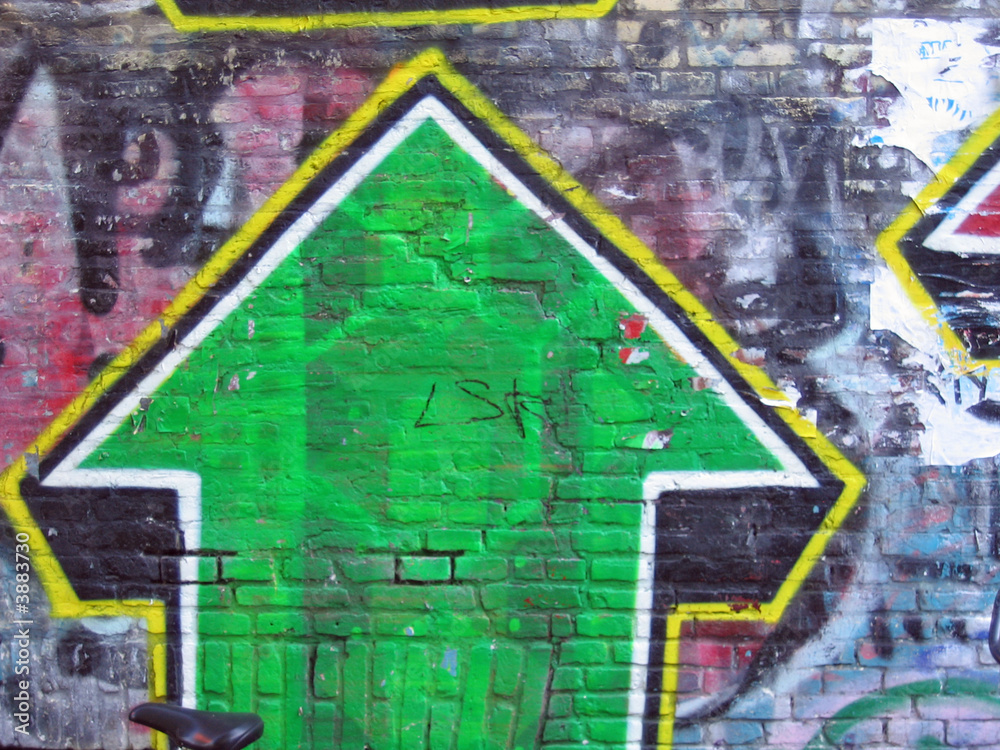 Graffiti of a green arrow on bricks wall