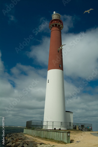 Barnegat Lighthouse with seagulls, blue sky, and white clouds