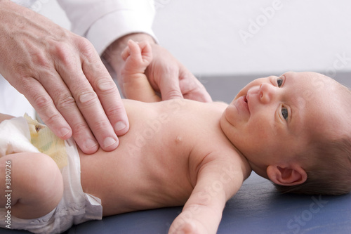 A doctor using his hands to palpate a newborn's abdomen