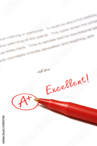 A paper is graded A Plus, Excellent, with red pen. photo