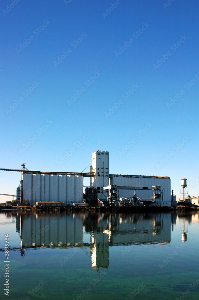Naklejka premium Waterfront Grain Silo Reflected near Seaport Loading Docks