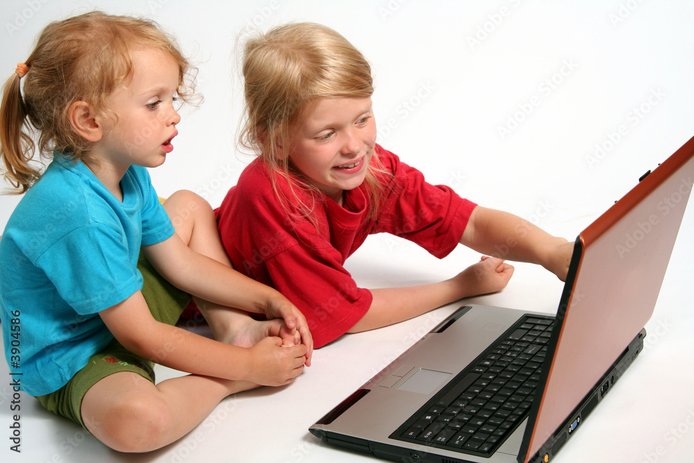 Two little girls playing on laptop on a white background Two little girls playing on laptop on a white background