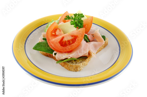 Ham lettuce tomato and cheese open sandwich on wholemeal bread.