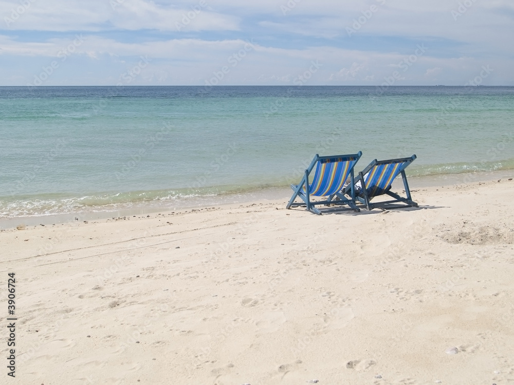 Two lawn chairs on a deserted beach