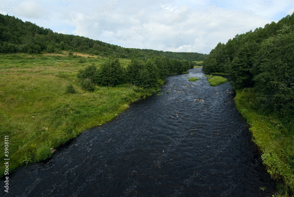 deep blue waters of the river, green grass and blue sky deep blue waters of the river, green grass and blue sky