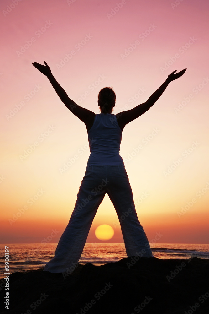 Woman in meditation pose at sunset with falling sun