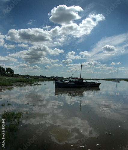 Clouds reflected with abandoned trawler rising with the tide