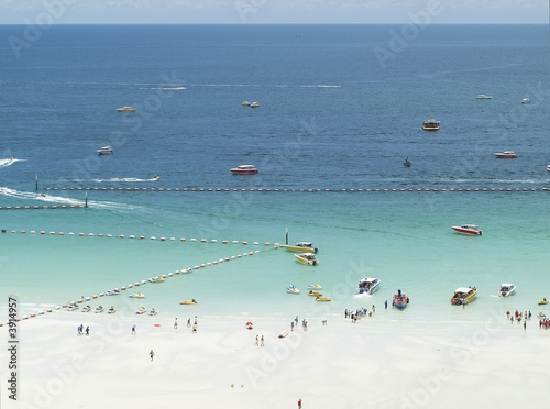 White, tropical beach and speedboats picking up passengers